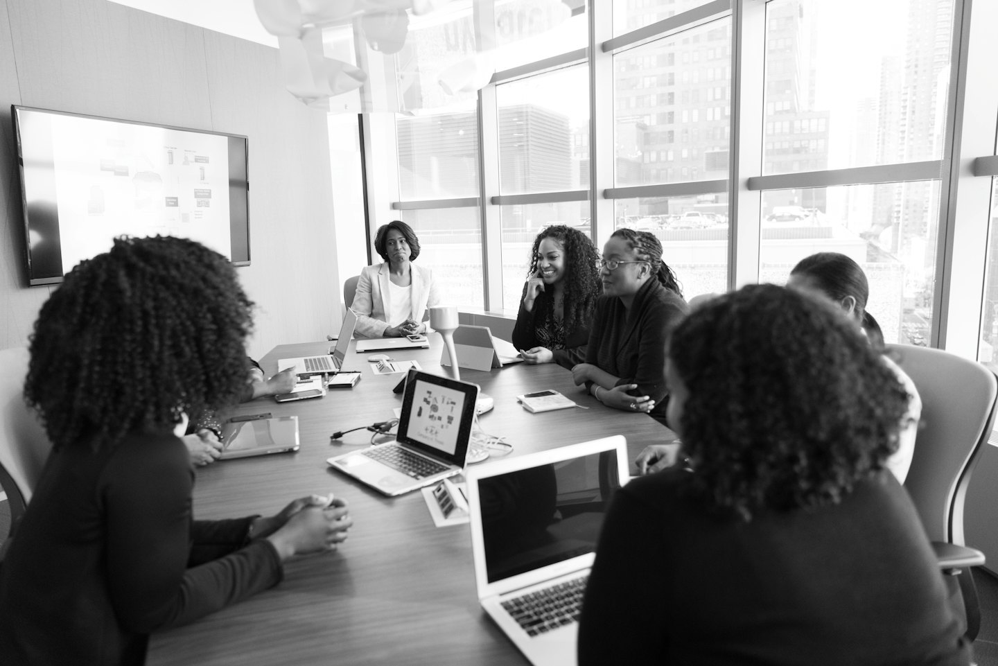 Black women collaborate around a conference table with laptops.