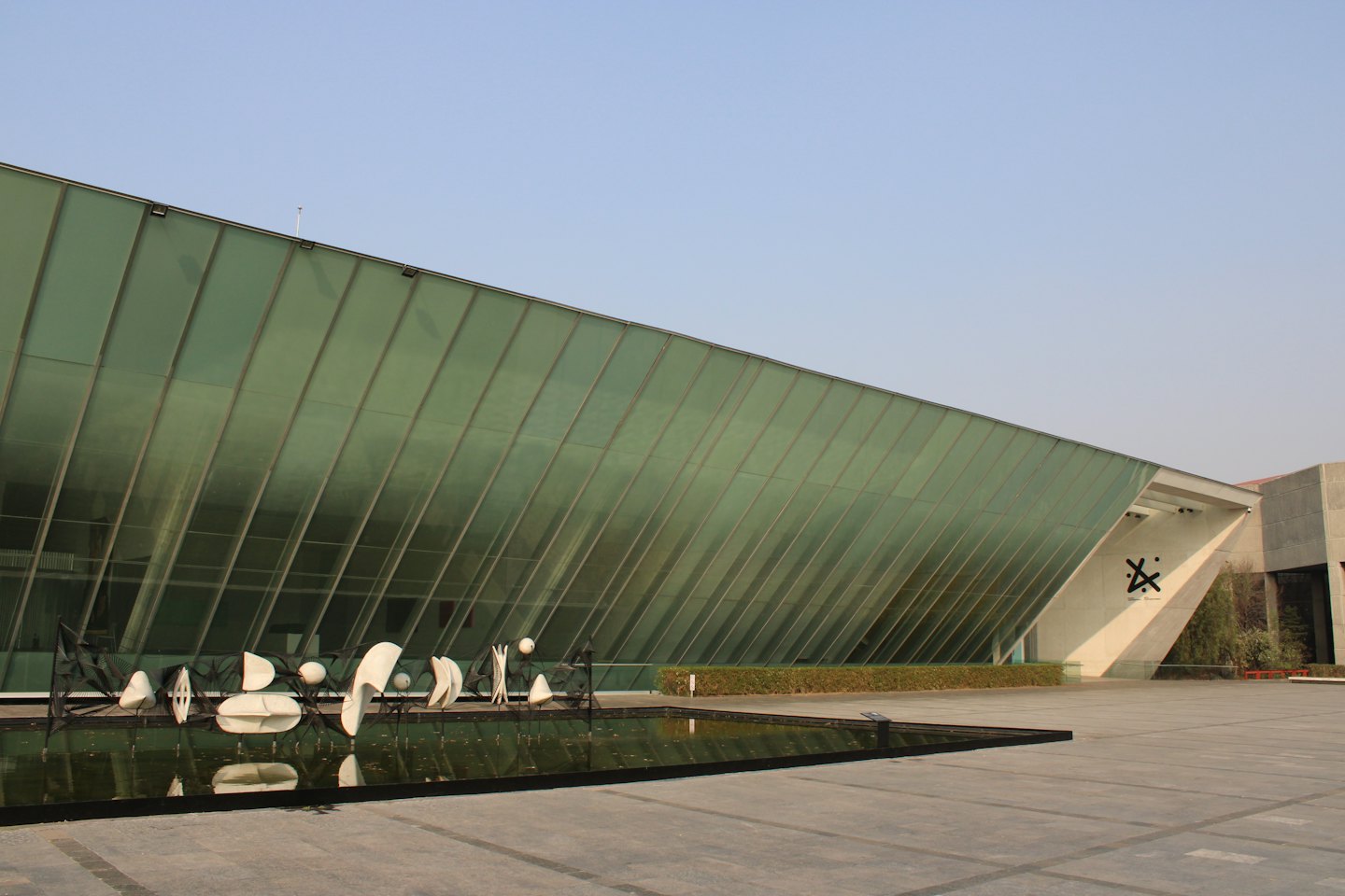 Modern corporate building with a sculpture in a reflecting pool.