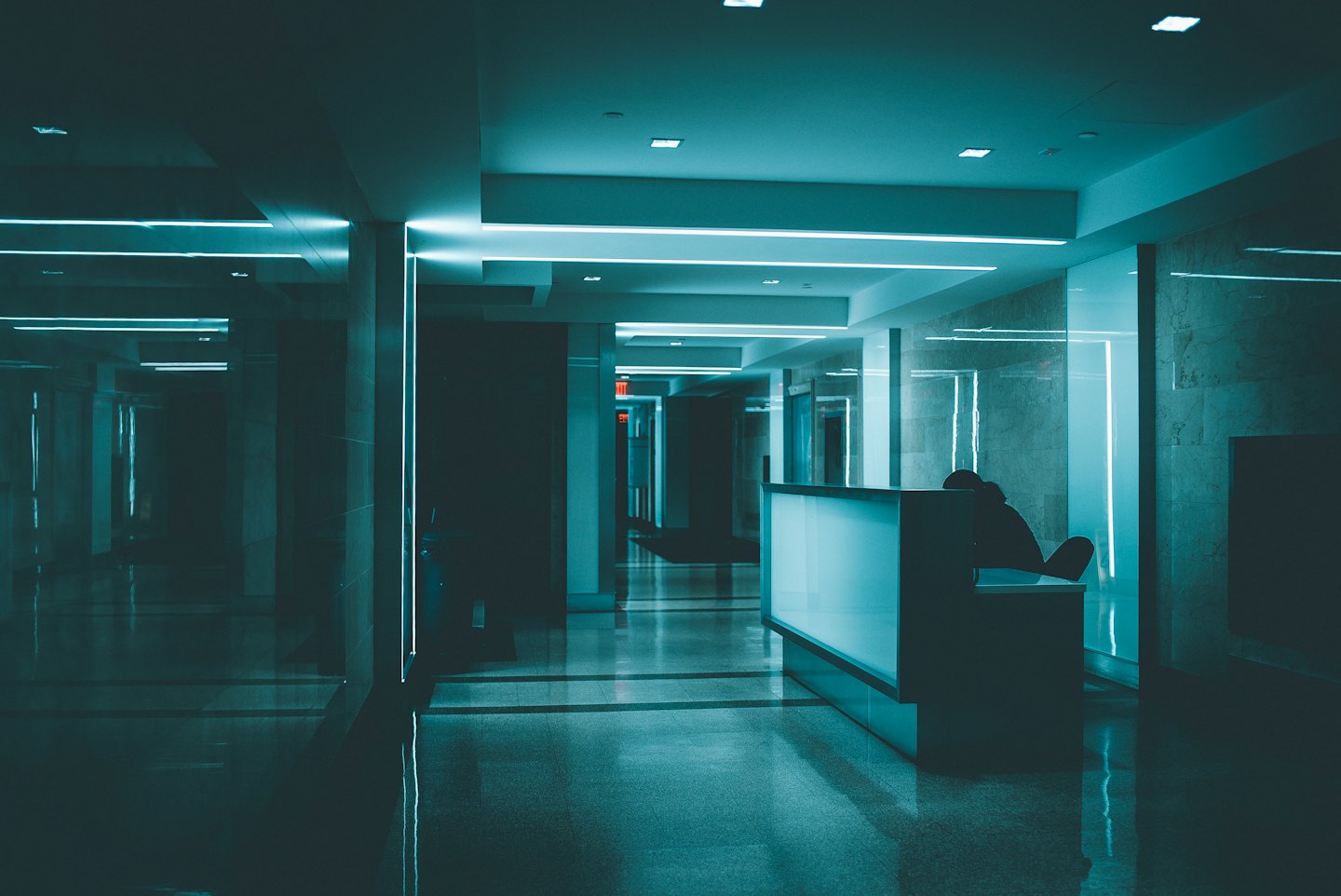 Receptionist seated at a modern desk with cyan lighting.