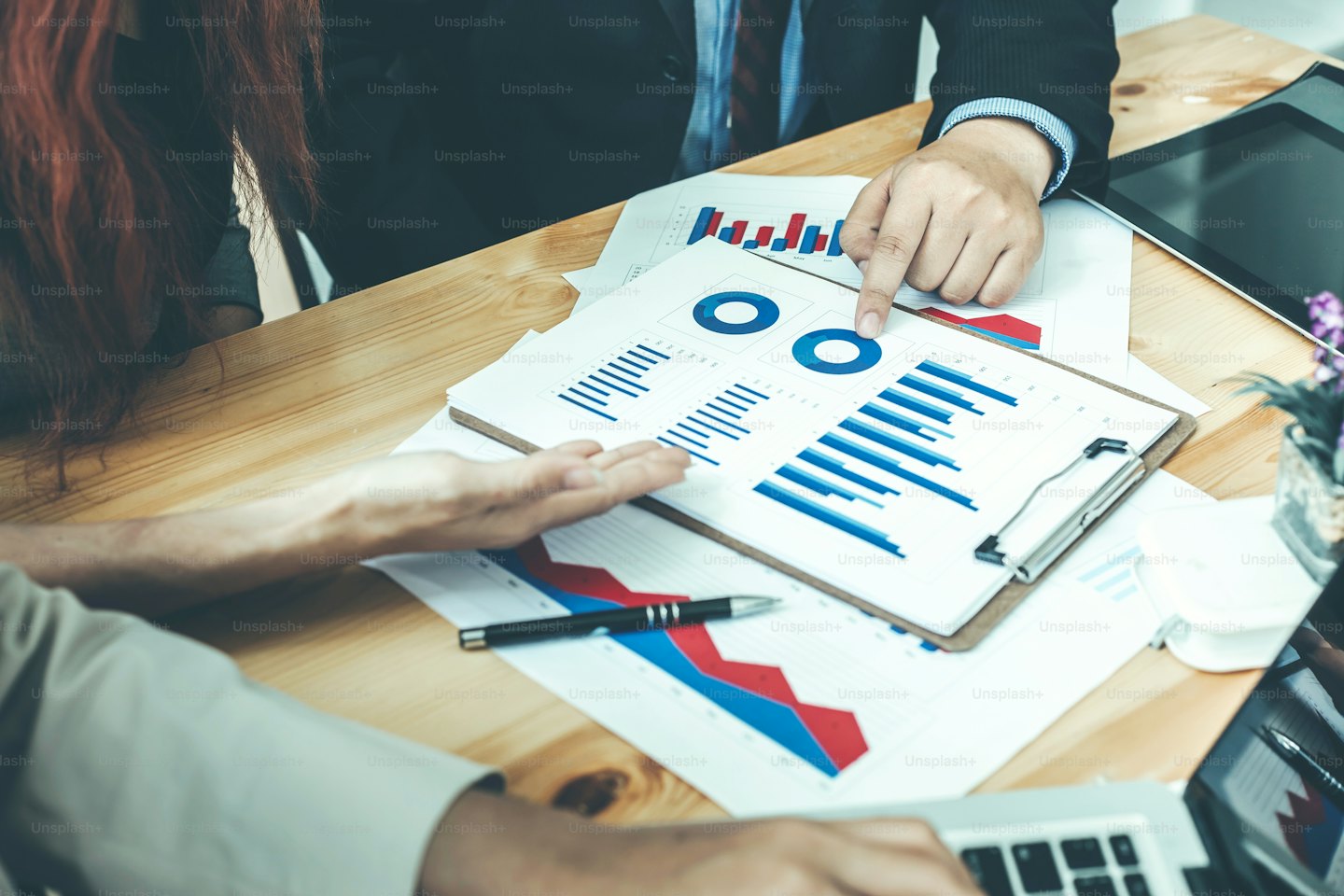 Two professionals discuss financial data over a wooden table.